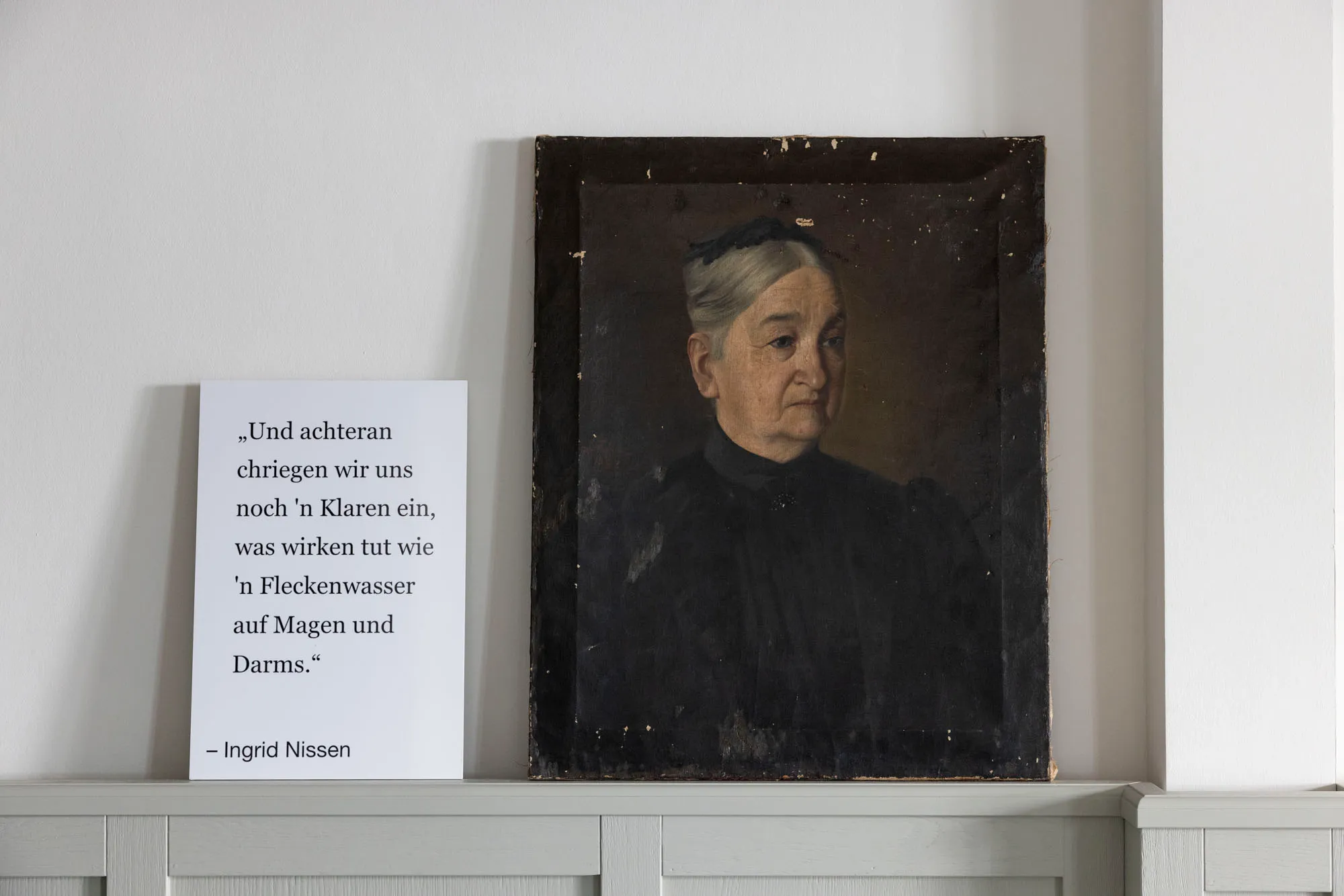 Altes Ölporträt einer Dame neben einer Tafel mit plattdeutschem Spruch