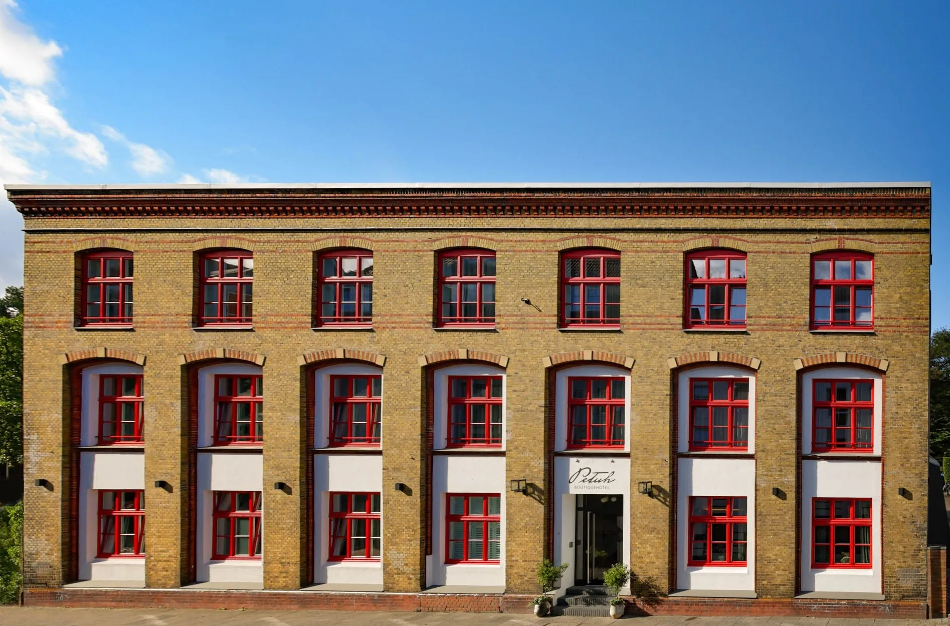 Backsteinfassade des Boutiquehotels Petuh mit roten Sprossenfenstern